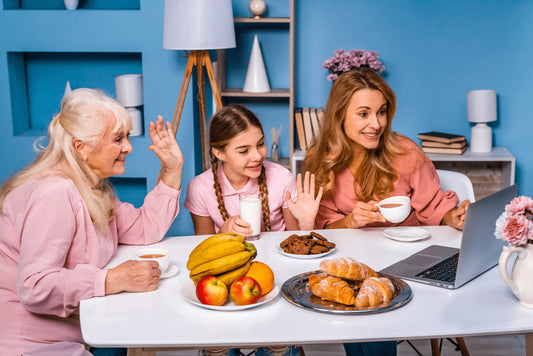 Three generations of women on a video call with fruit, milk, and pastries on the table, representing family wellness and connection across ages.