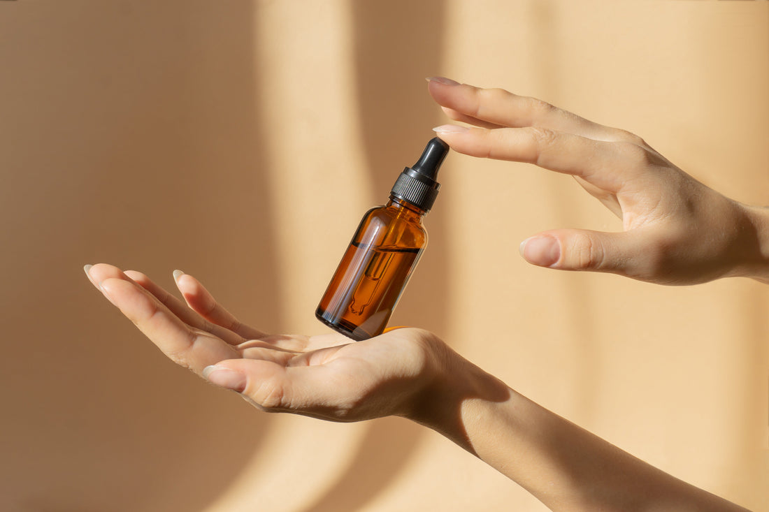 Hands holding a dropper bottle over a neutral background