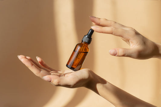 Hands holding a dropper bottle over a neutral background