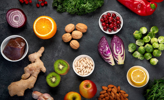 An overhead flat lay of nutrient-rich foods including fruits, vegetables, nuts, and a bowl of liver, representing a balanced diet and essential vitamins and minerals.