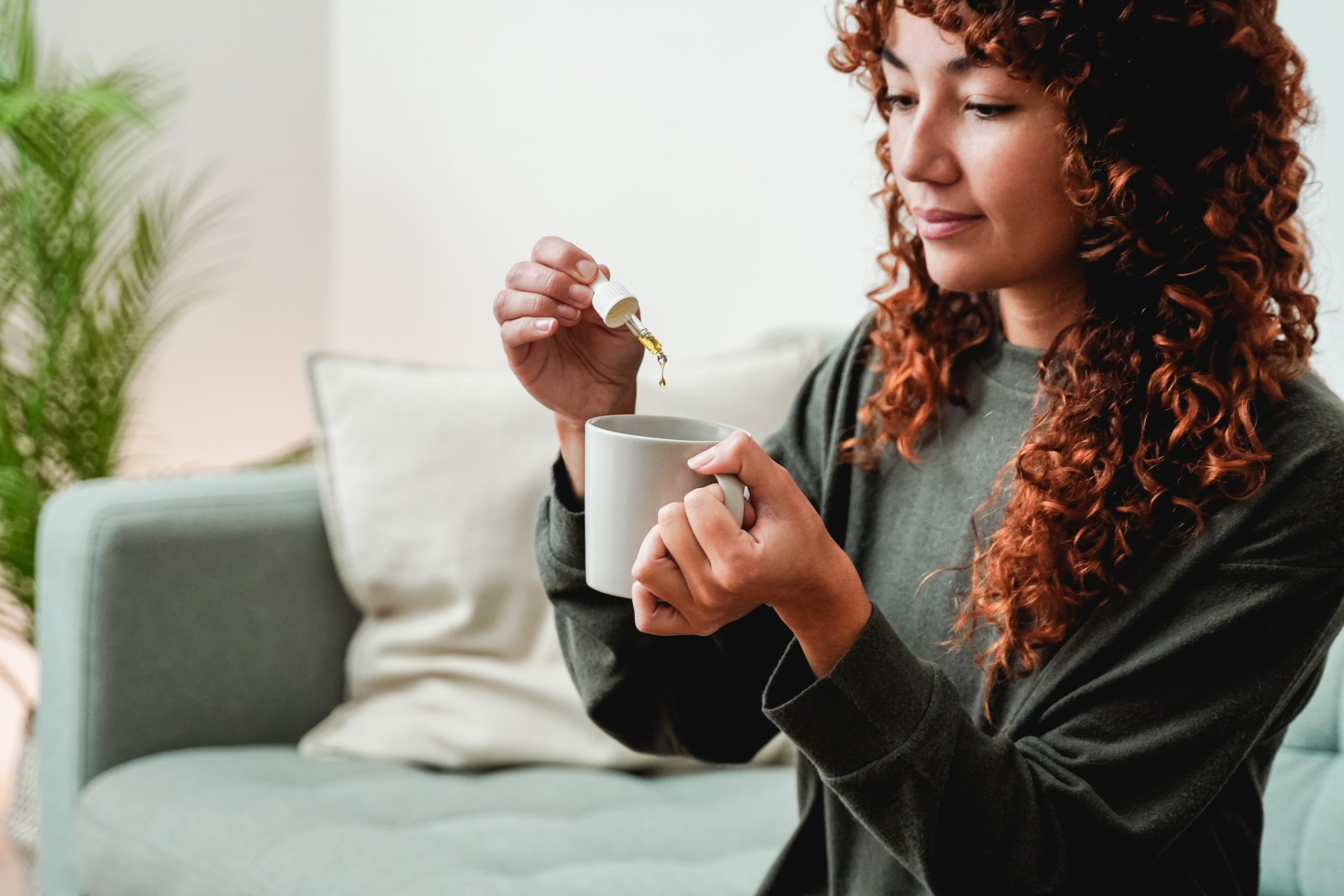 A young woman adding liquid to a mug using a dropper. 